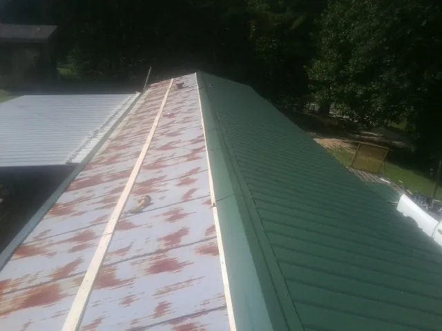 Old rusted panels beside newly installed green metal roofing — Wind Damage Roof Repair by Roofing Brothers in Sweetwater
