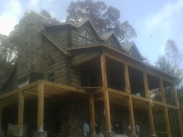Stone chimney and dormers on a large log home with a timber porch in Sweetwater